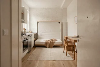 Intérieur d'un studio compact bien agencé d'environ 20 m² avec lit escamotable, kitchenette et parquet clair en ville